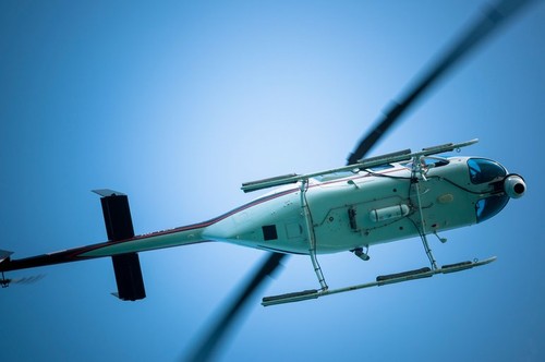 Chopper or Helicopter flying overhead, above sea, in the sky. Coast guard helicopter hovering close and overhead.