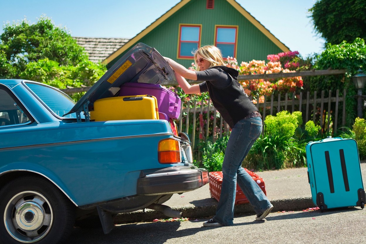 Woman loading car trunk with colorful suitcases