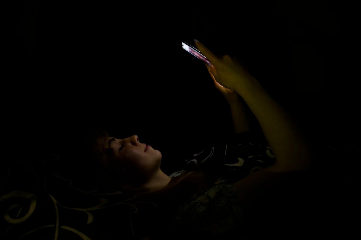 The girl is lying with a mobile phone.