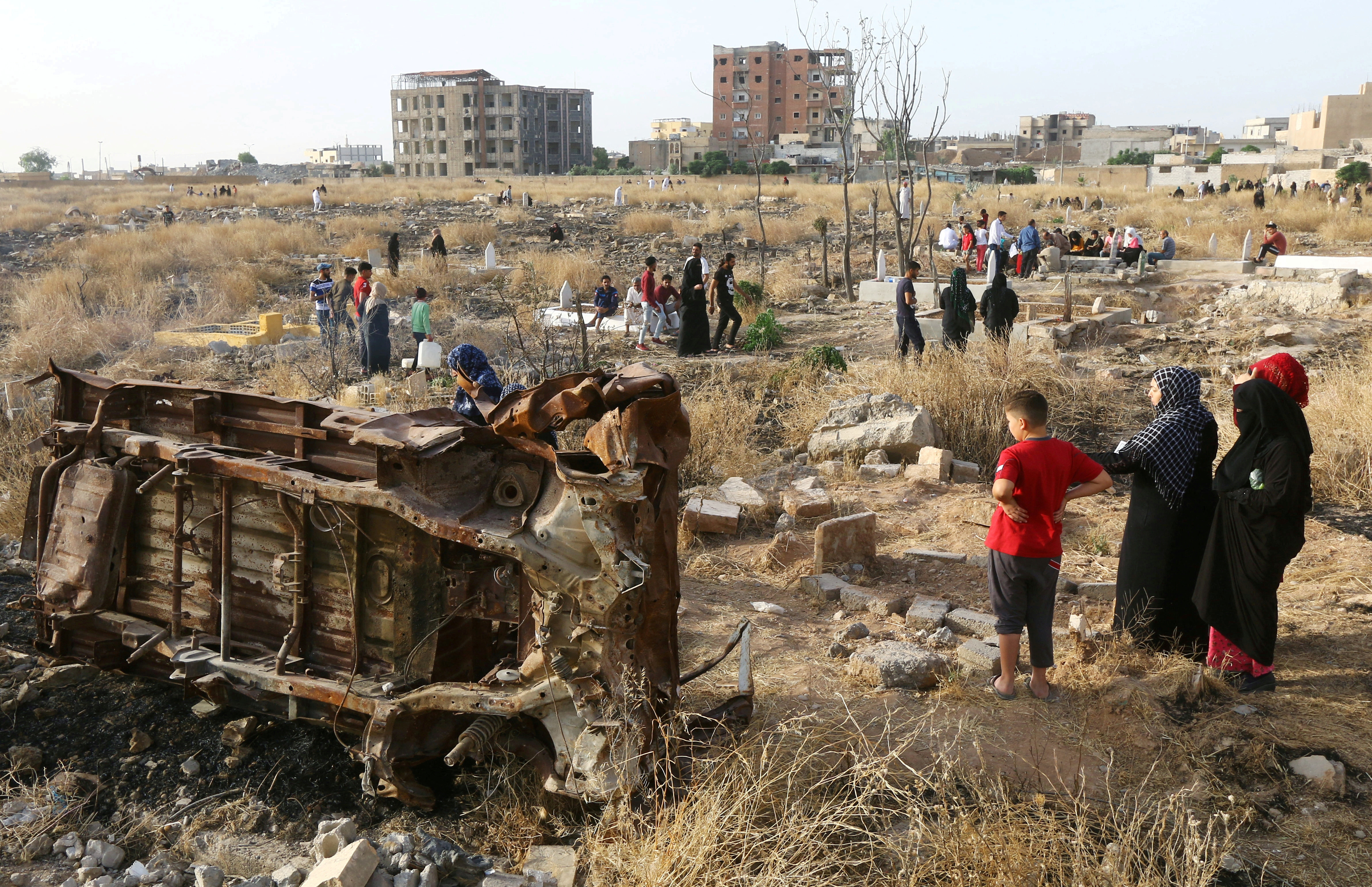 FILE PHOTO: People visit the graves of their loved ones during the first day of the Muslim holiday of Eid al-Fitr in Raqqa