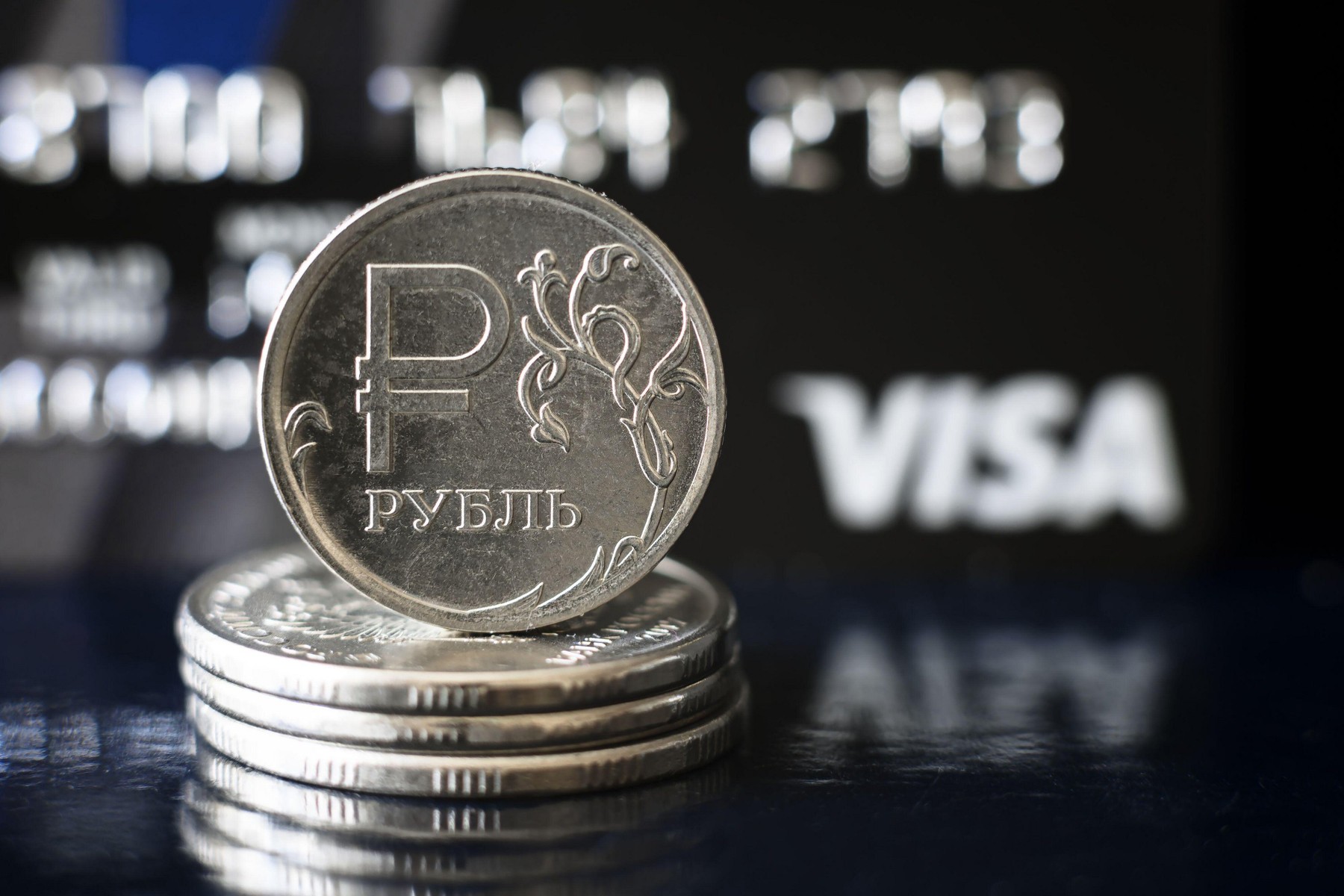 Moscow - March 6, 2022: Ruble coin and Visa credit card, Russian money is under pressure from sanctions. Concept of currency, cancelled transactions a