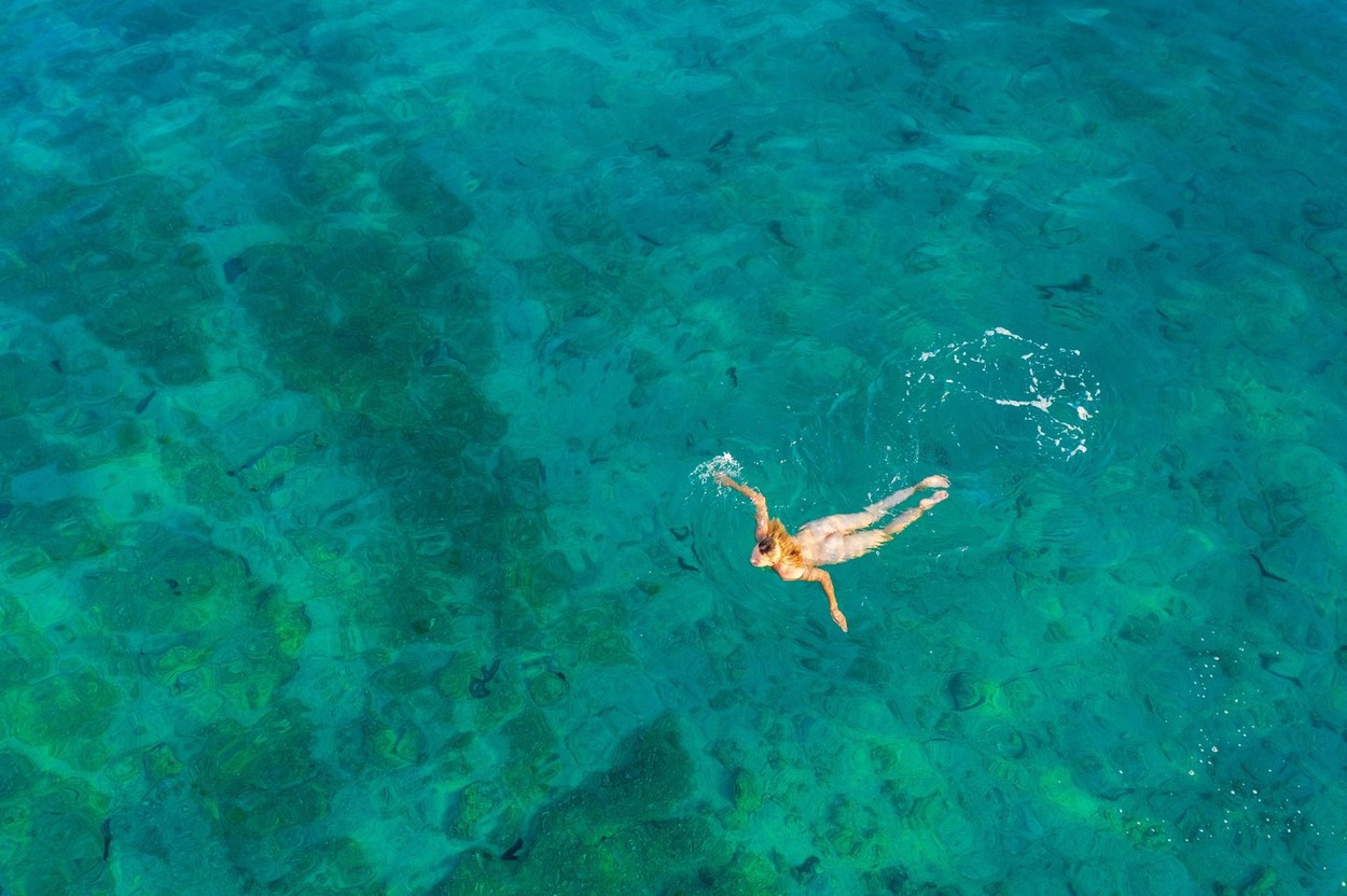 Aerial view of a naked girl swimming in sea