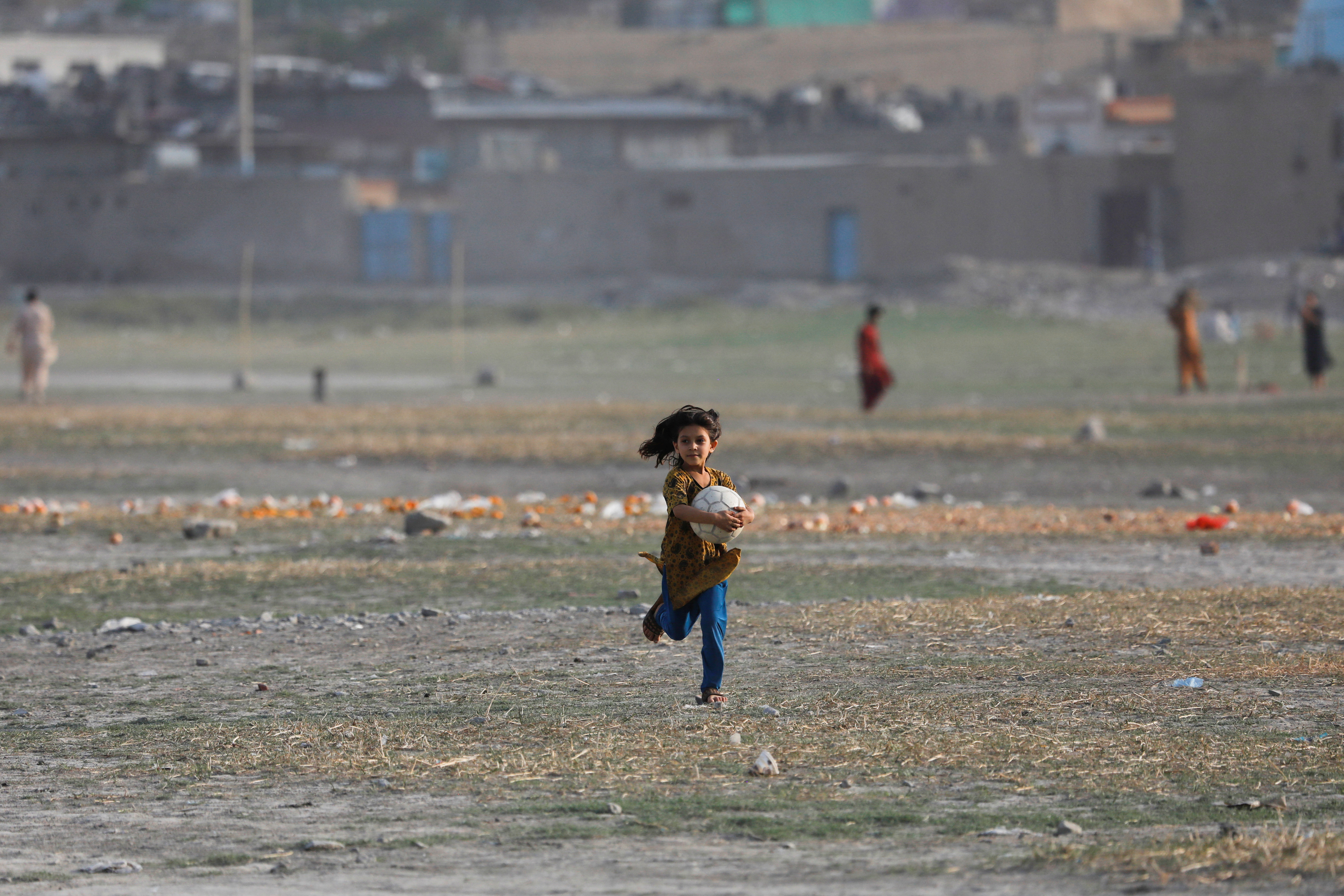 An Afghan girl carries a ball in Kabul
