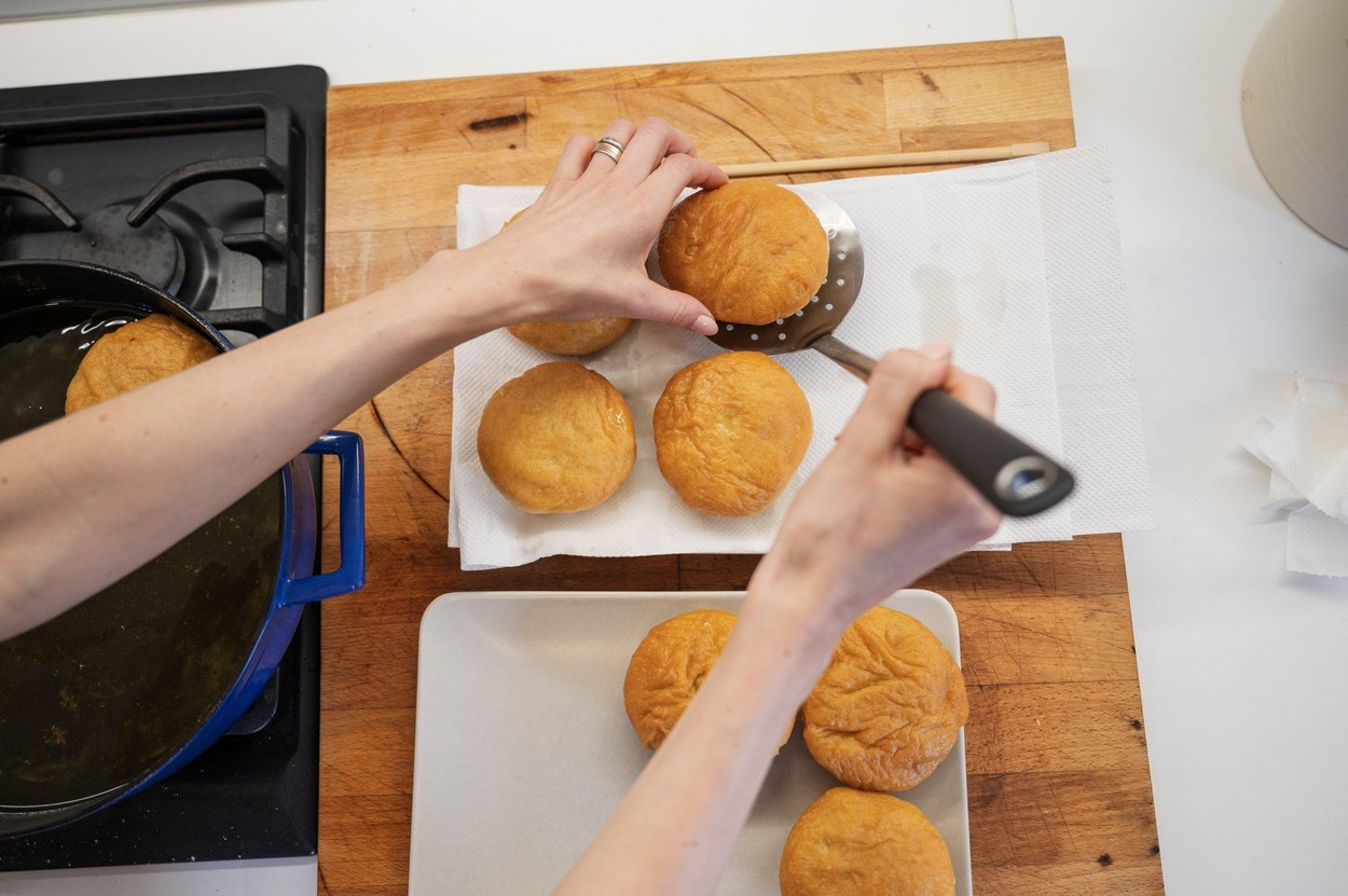 Top view of a woman placing freshly baked home made vegan doughnuts on a paper towel.