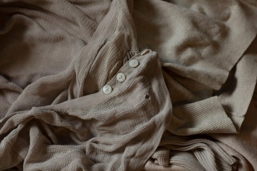 Old clothes in washed out colors laying on a pile. Different pieces with holes and stains ready to be recycled, circular economy principle. Fashion in