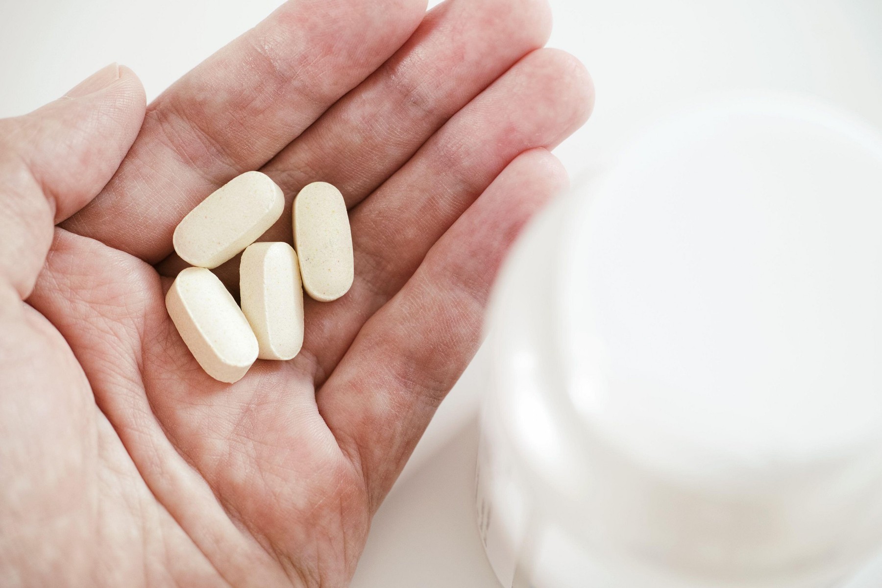 A man holding magnesium taurate tablets in his hand. Close up.