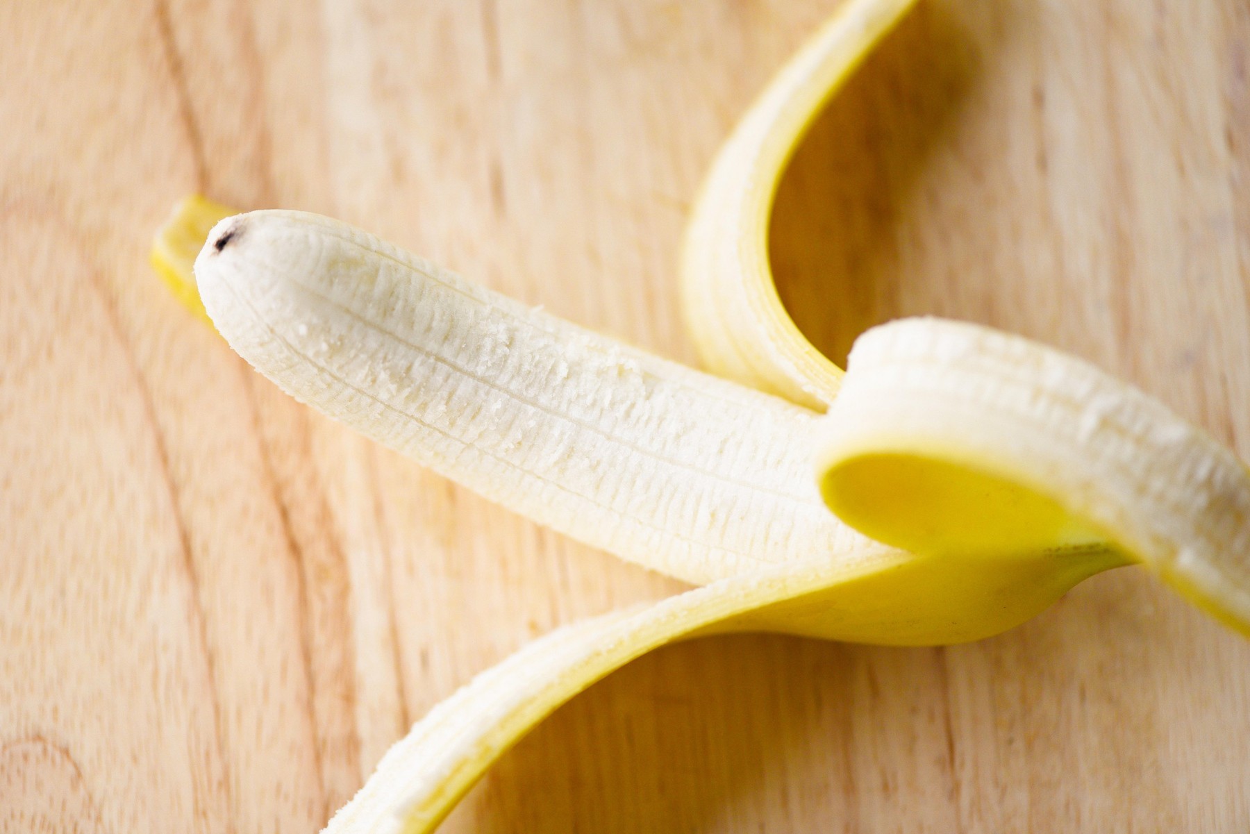 Banana peel / Close up of fresh ripe a banana fruit peeled on wooden board