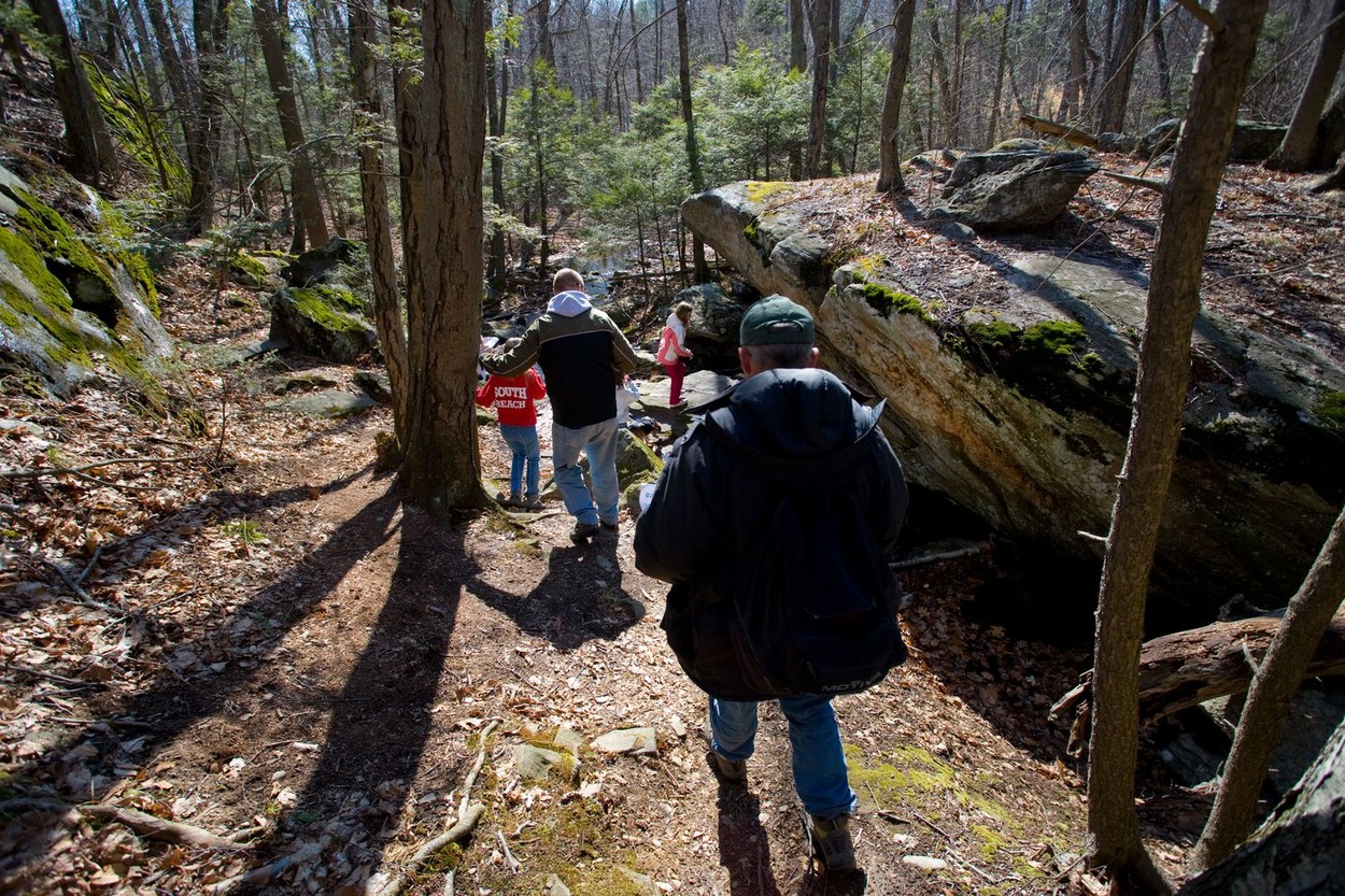 A family uses a hand-held GPS unit to find a Geocache or Geo Cache which is a hiking activity where people search for boxes