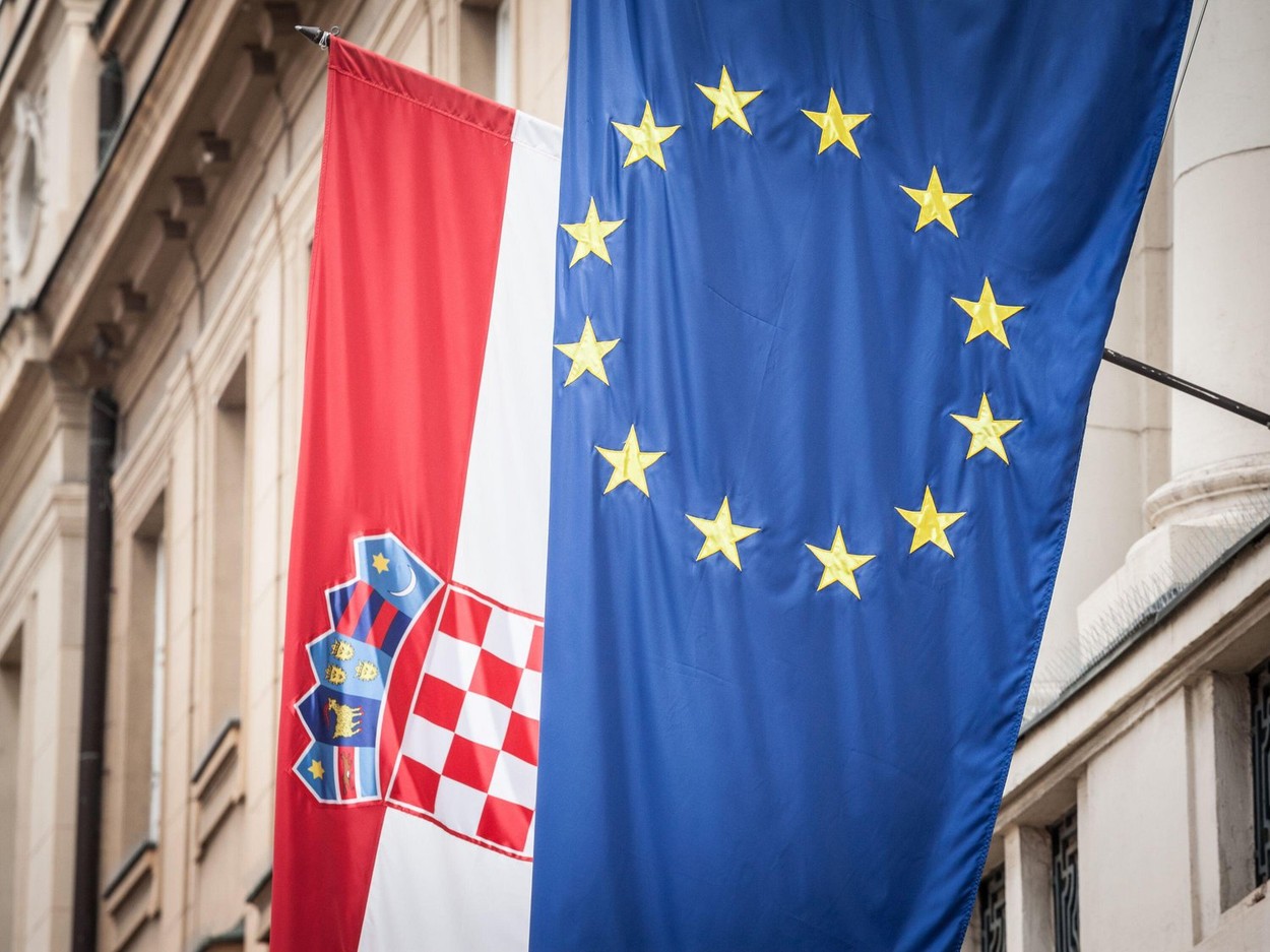 Picture of the flags of Croatia and the EU waiving in the air in front of a building. The 2013 enlargement of the European Union saw Croatia join the