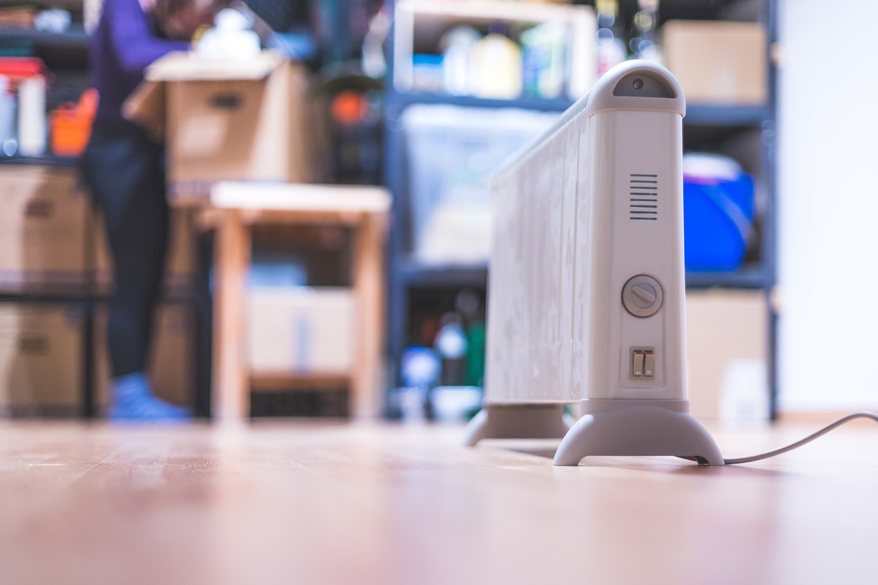 Heating the basement with electric heater. Blurry boxes and shelfs in the background
