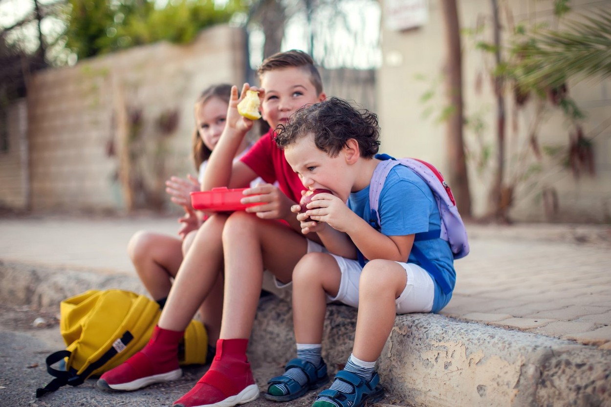 Pupils having a snack outdoor. Children, education and nutrition concept