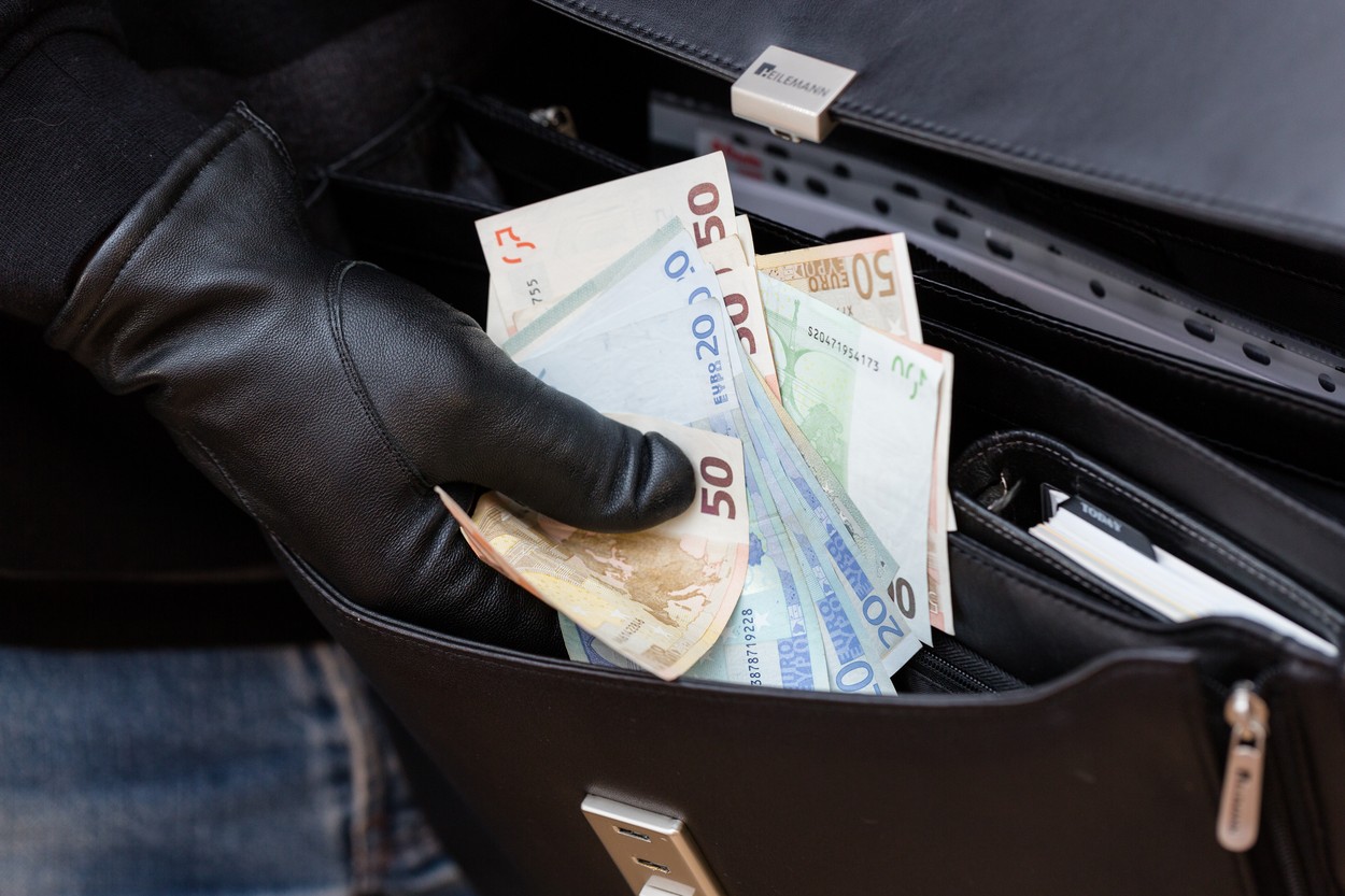 hand in leather glove stealing money from briefcase