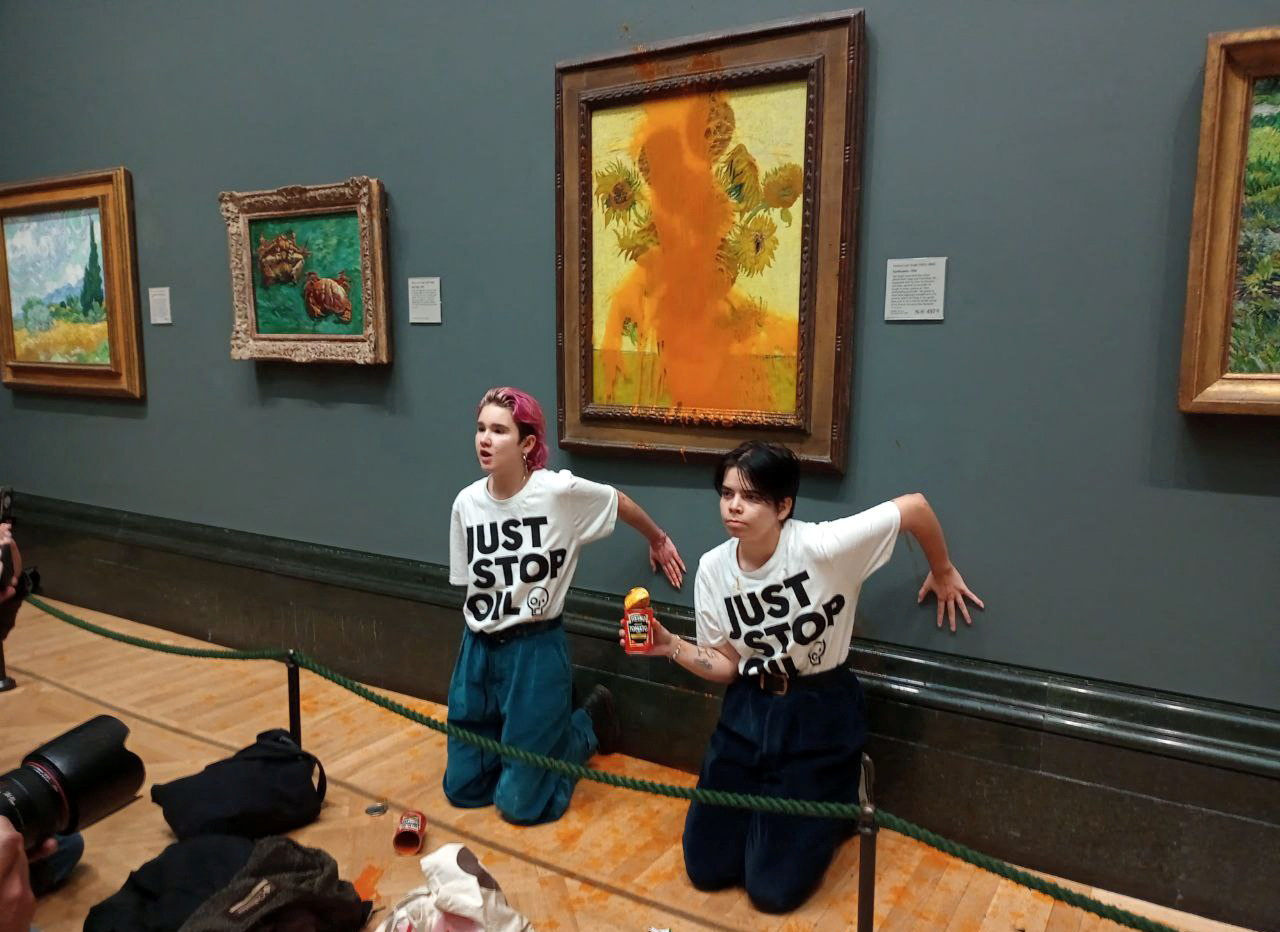 Activists of "Just Stop Oil" glue their hands to the wall after throwing soup at a van Gogh's painting "Sunflowers" at the National Gallery in London