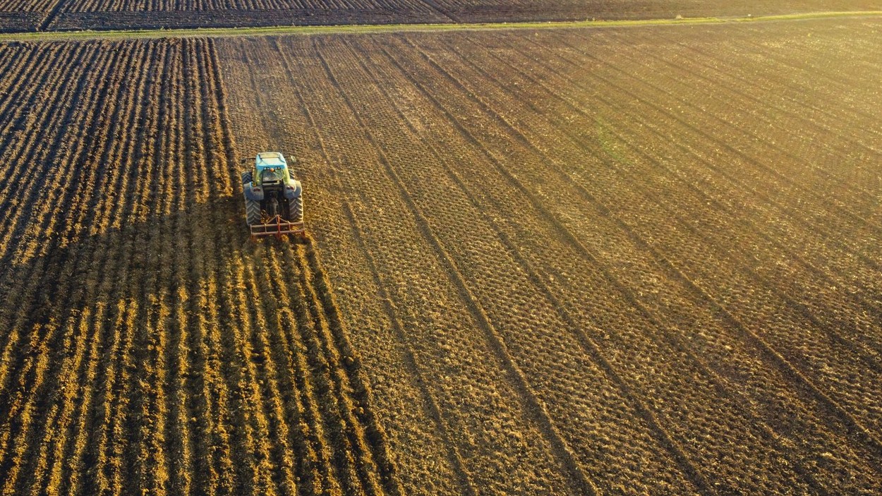 farmer with tractor leveling land in the countryside.