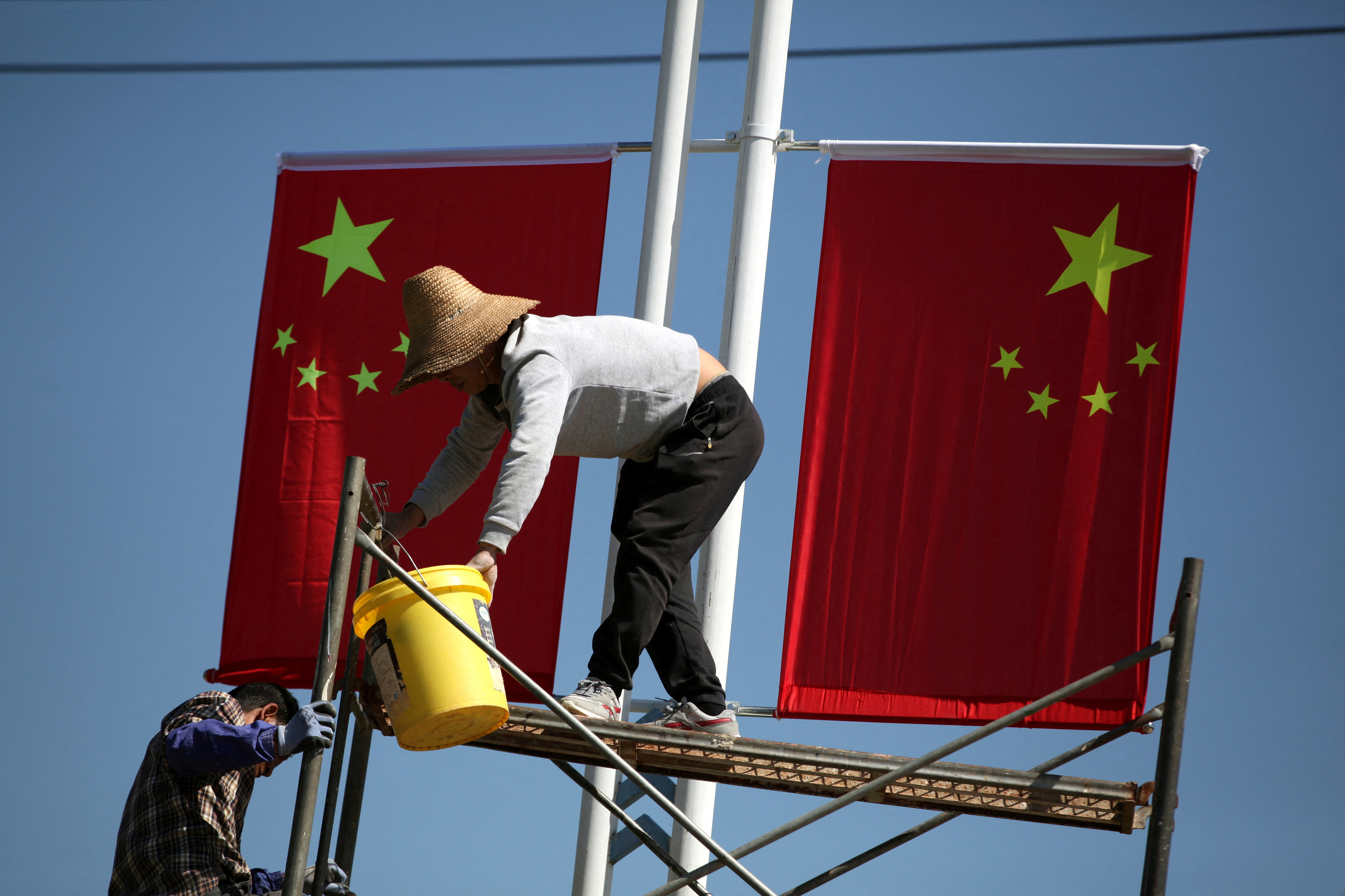 FILE PHOTO: Workers hang up Chinese flags on a street ahead of the 70th founding anniversary of People's Republic of China in Kunming, Yunnan