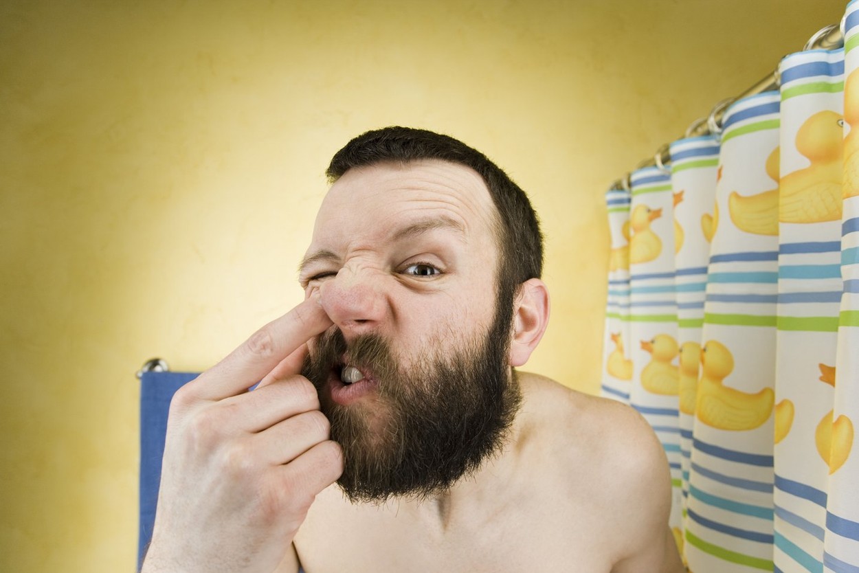 Man with beard in bathroom picking nose