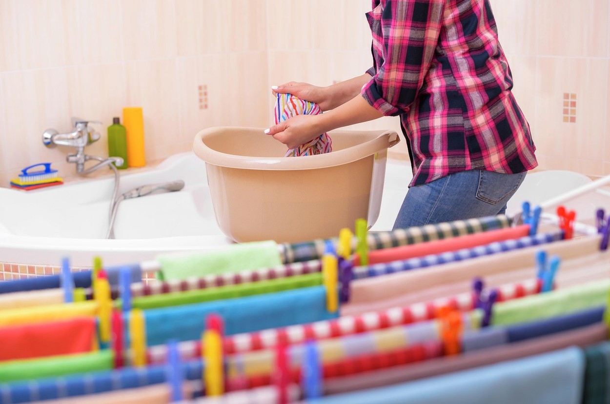 Women's hands wash clothes in the container. Close-up.