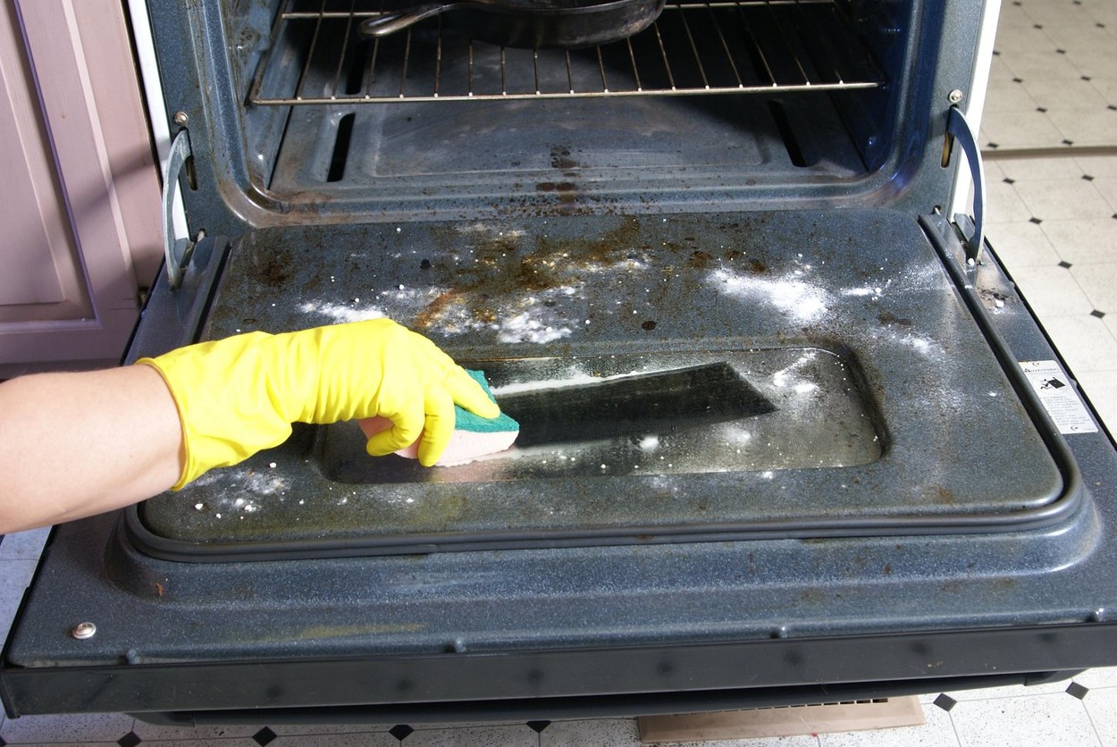 Cleaning the oven door with baking soda, water and a sponge