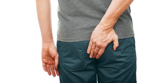 Man holds his butt with his hand because he has a hemorrhoid disease, and him painfully. Diagnostics and treatment of hemorrhoids