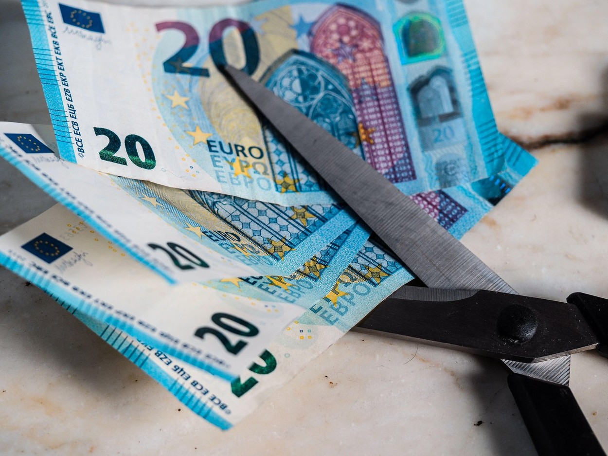 Cutting emission and debt avoiding loss of value. Euro money currency placed inside a pair of scissors