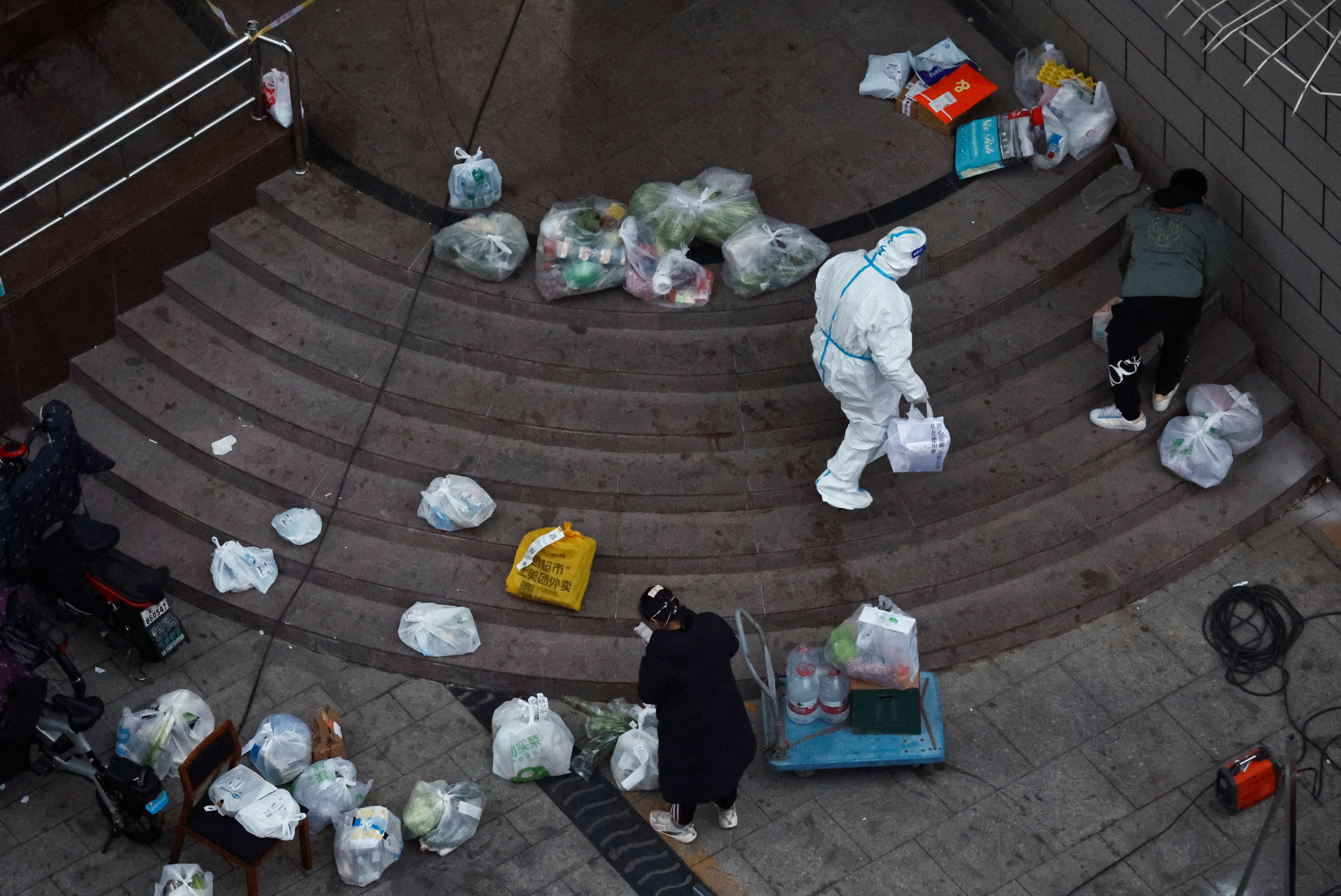 A worker in a protective suit moves delivery goods at a residential building that is under lockdown, following the coronavirus disease outbreak in Beijing