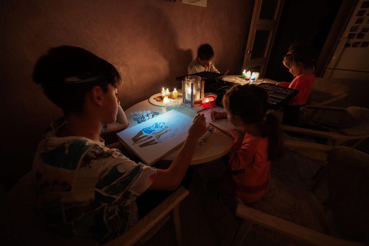 Family spending time together during an energy crisis in Europe causing blackouts. Kids drawing in blackout.