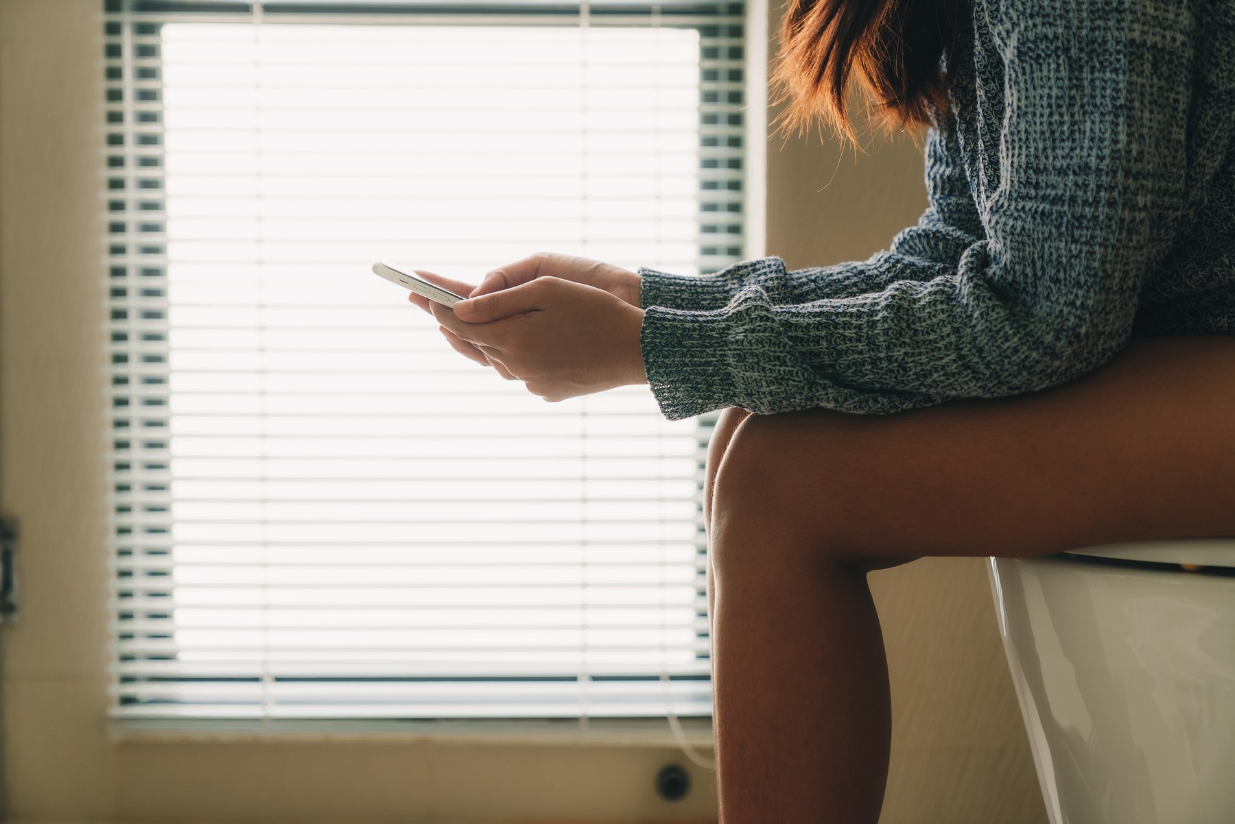 women using phone in toilet room in the morning