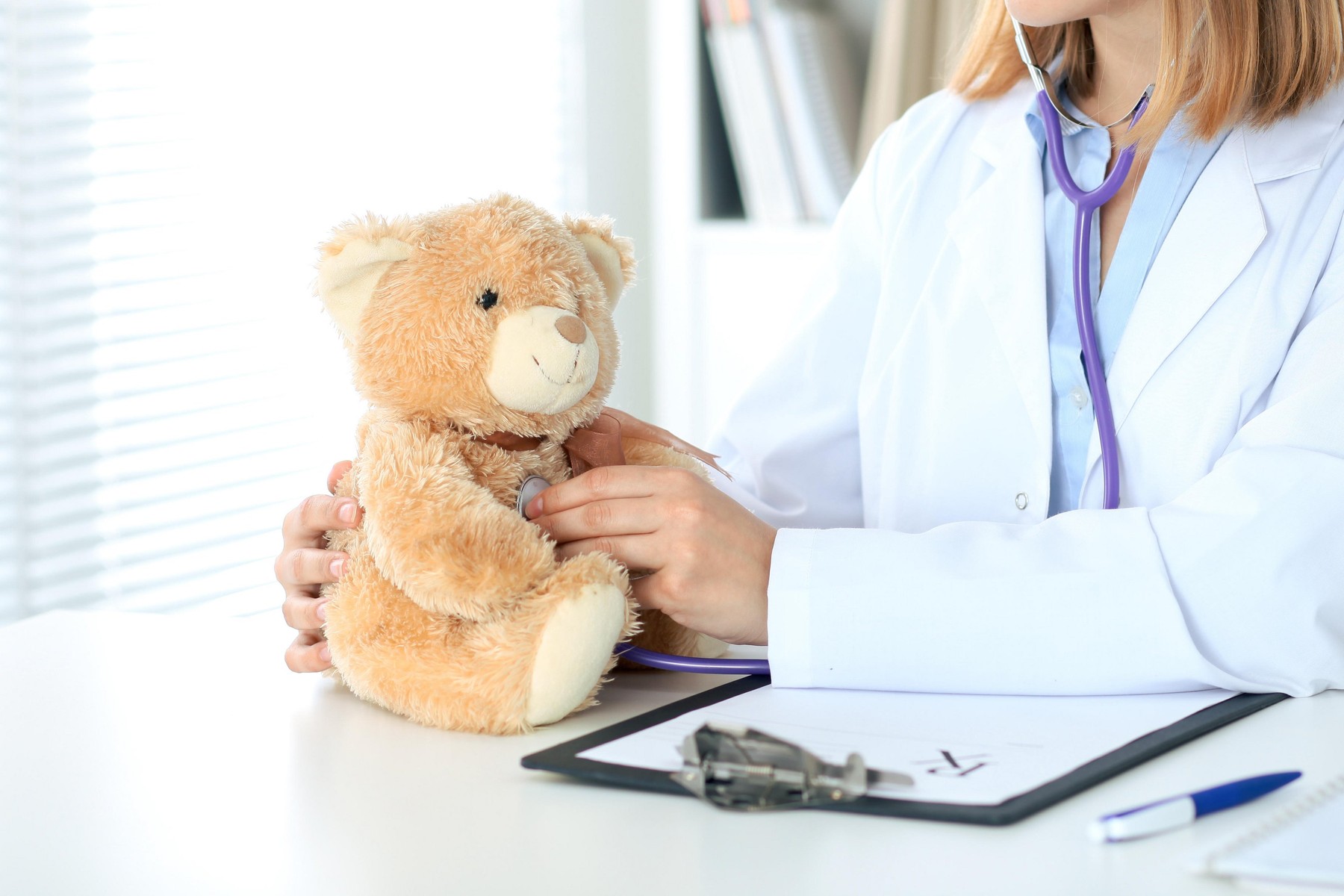 Female doctor examining a  Teddy bear  patient by stethoscope. Children medical care concept
