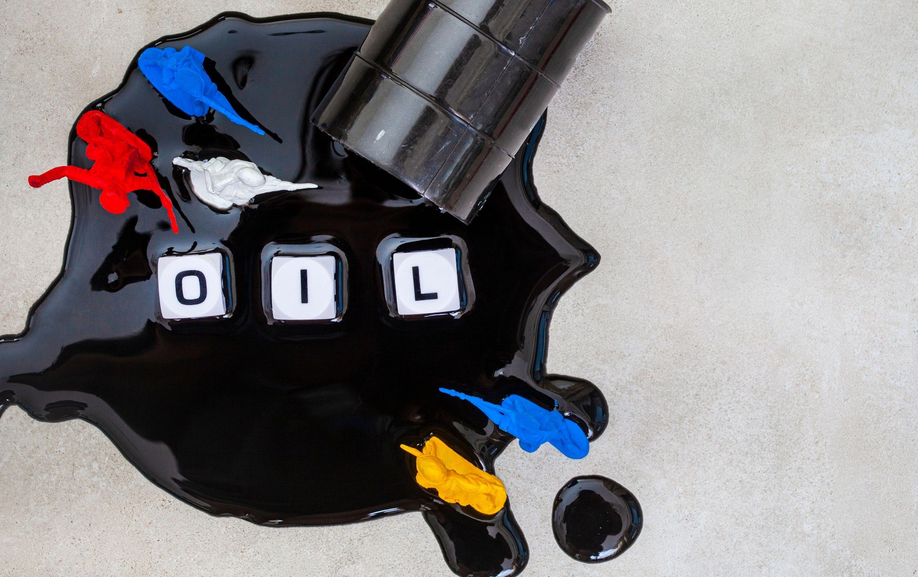 Oil crisis depiction with toys, oil barrel and spill on gray with lettering and Russian toy soldiers fighting Ukraine soldiers