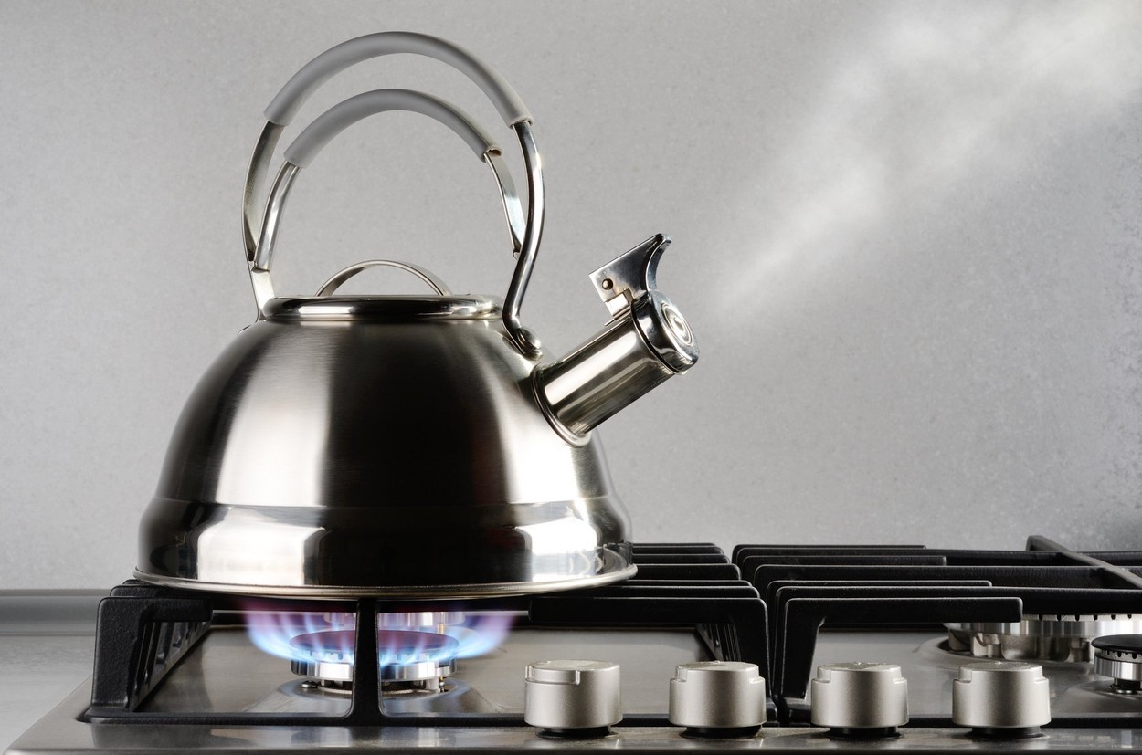 Tea kettle with boiling water on gas stove