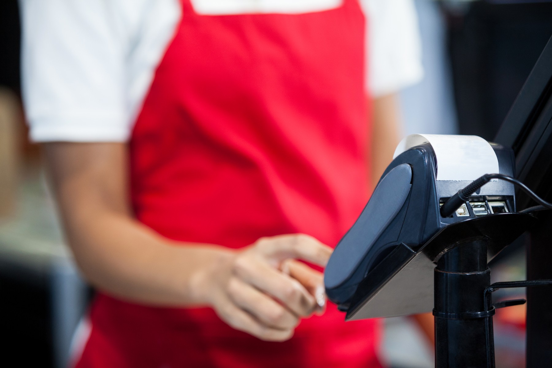 Female staff using credit card terminal at cash counter
