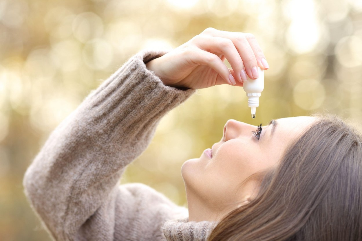 Close up of a woman with dry eyes applying artificial tear in winter in a park