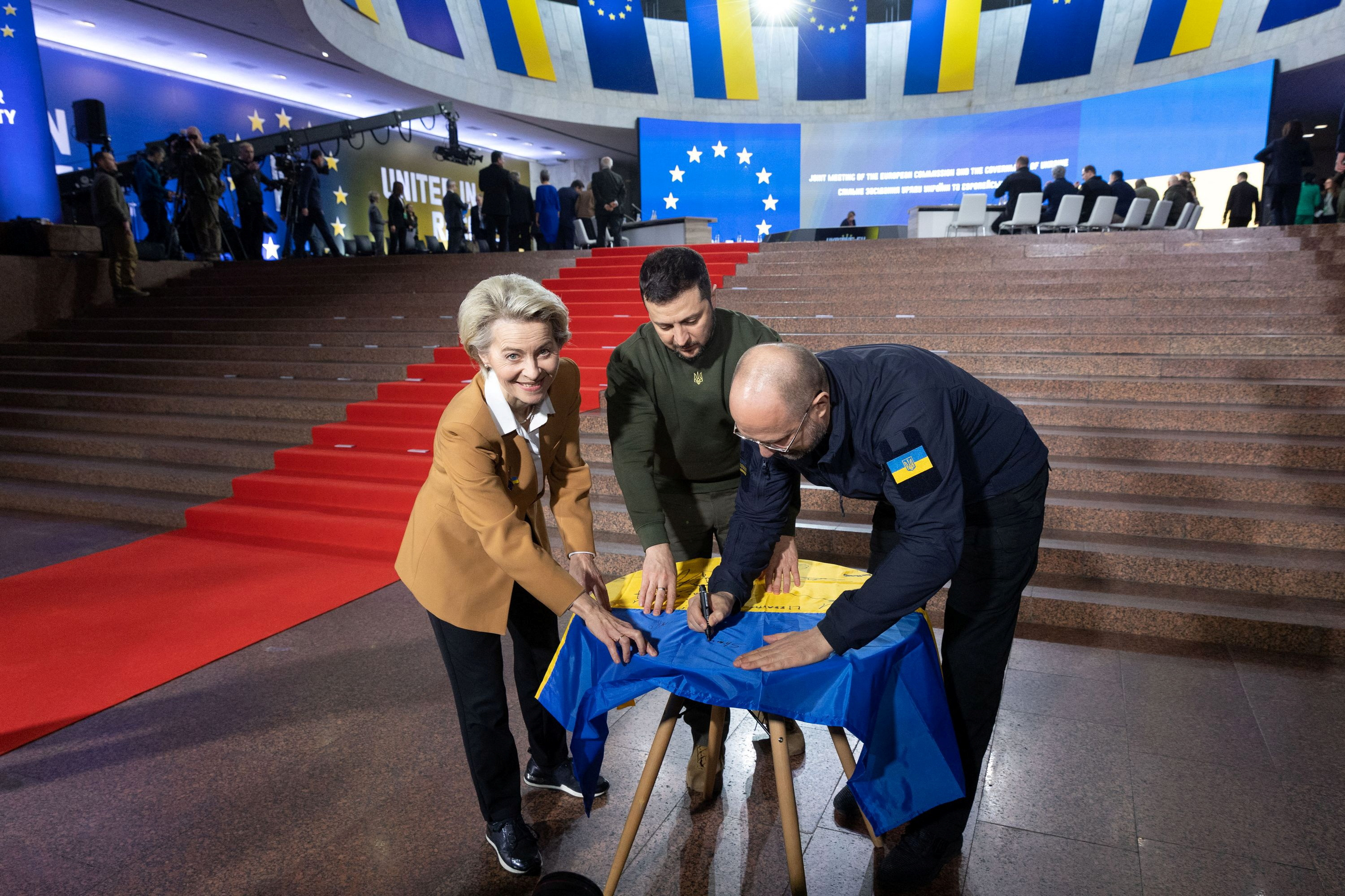 Ukraine's President Zelenskiy, Prime Minister Shmyhal and European Commission President von der Leyen sign a Ukrainian national flag before start of EU summit in Kyiv