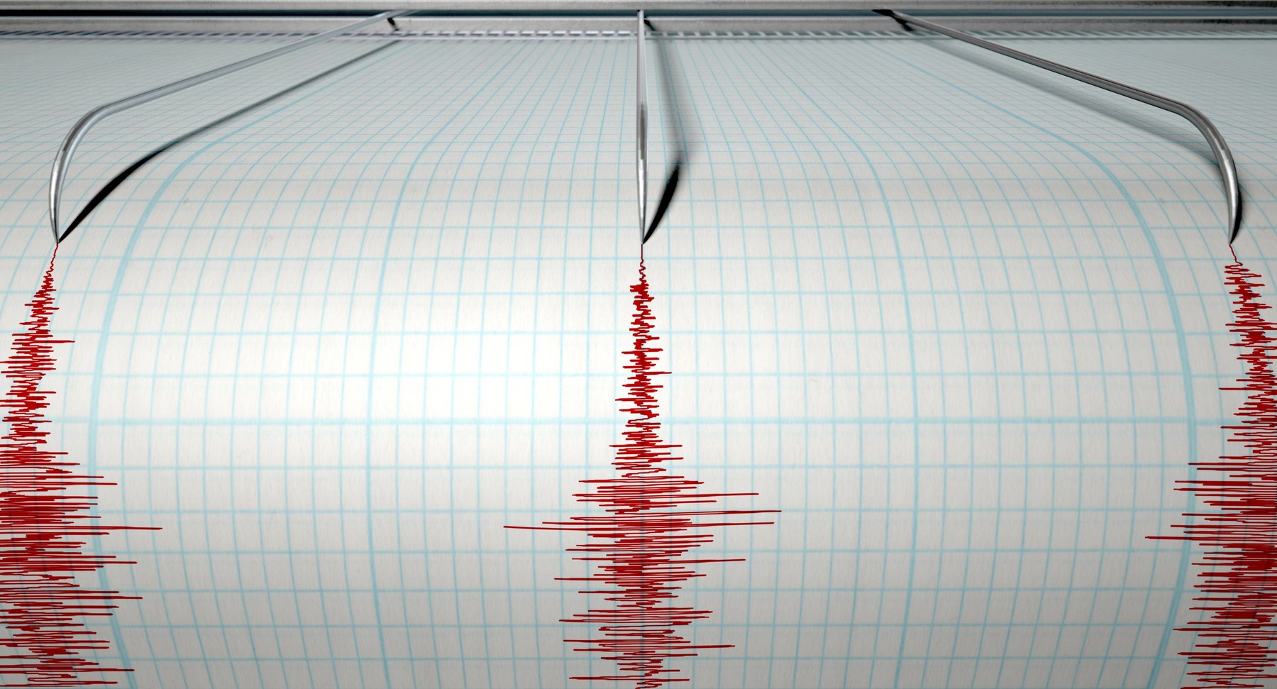 A closeup of a seismograph machine needle drawing a red line on graph paper depicting seismic and eartquake activity on an isola