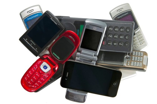 Pile of old and new mobile phones, including the Apple iPhone 4 and the Android phone Sony Ericsson Xperia X10 mini.