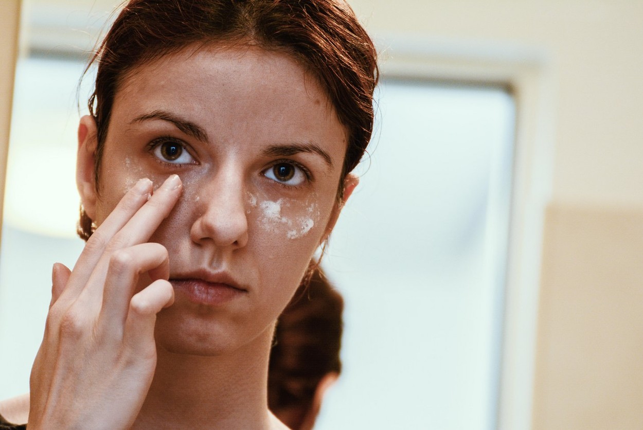 Redhead model using albumen or egg white to relieve the dark circles under her tired and puffy eyes