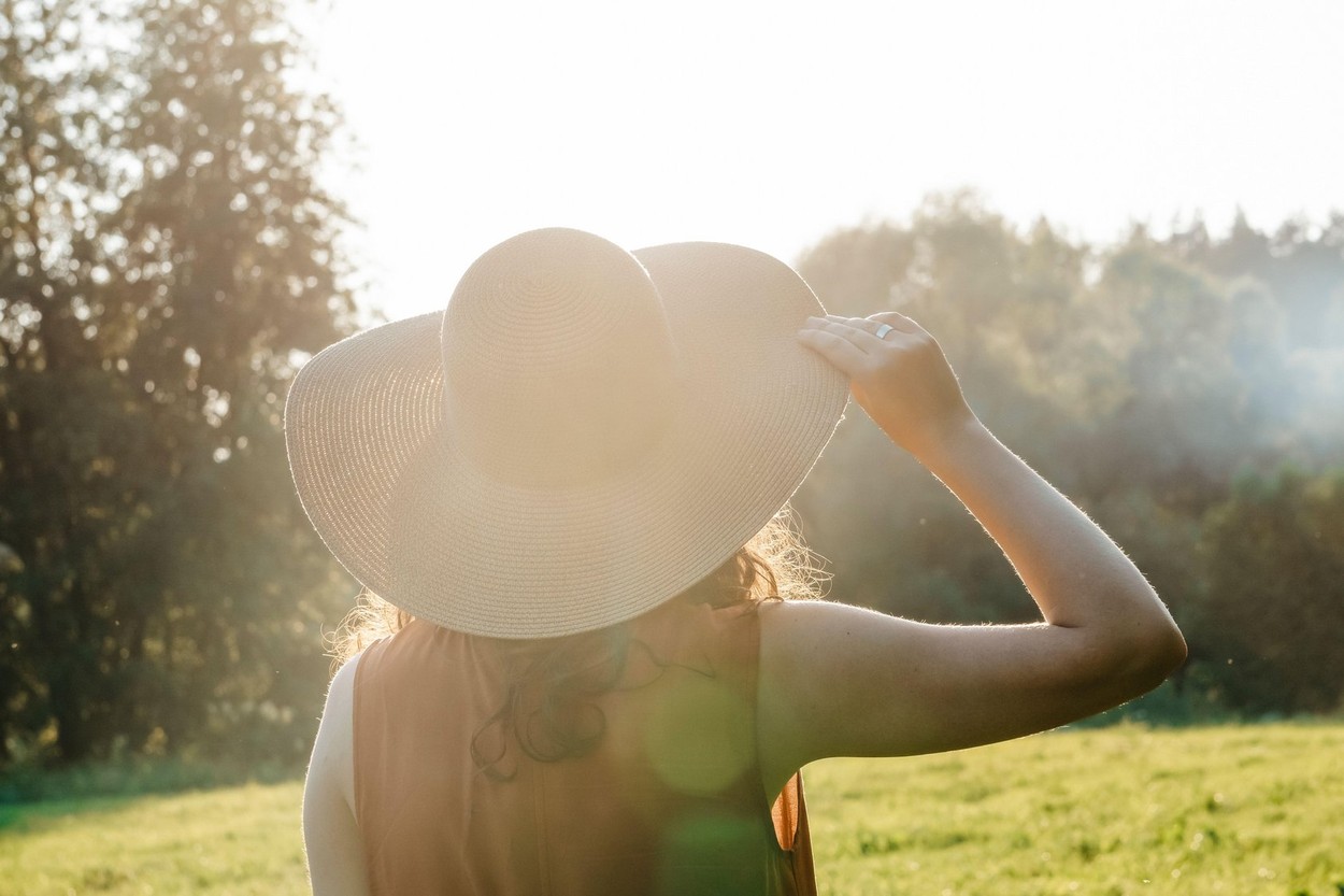 Happy girl in a hat enjoys life in a summer sunny field. Lifestyle, summer, relaxation, travel concept. High quality photo