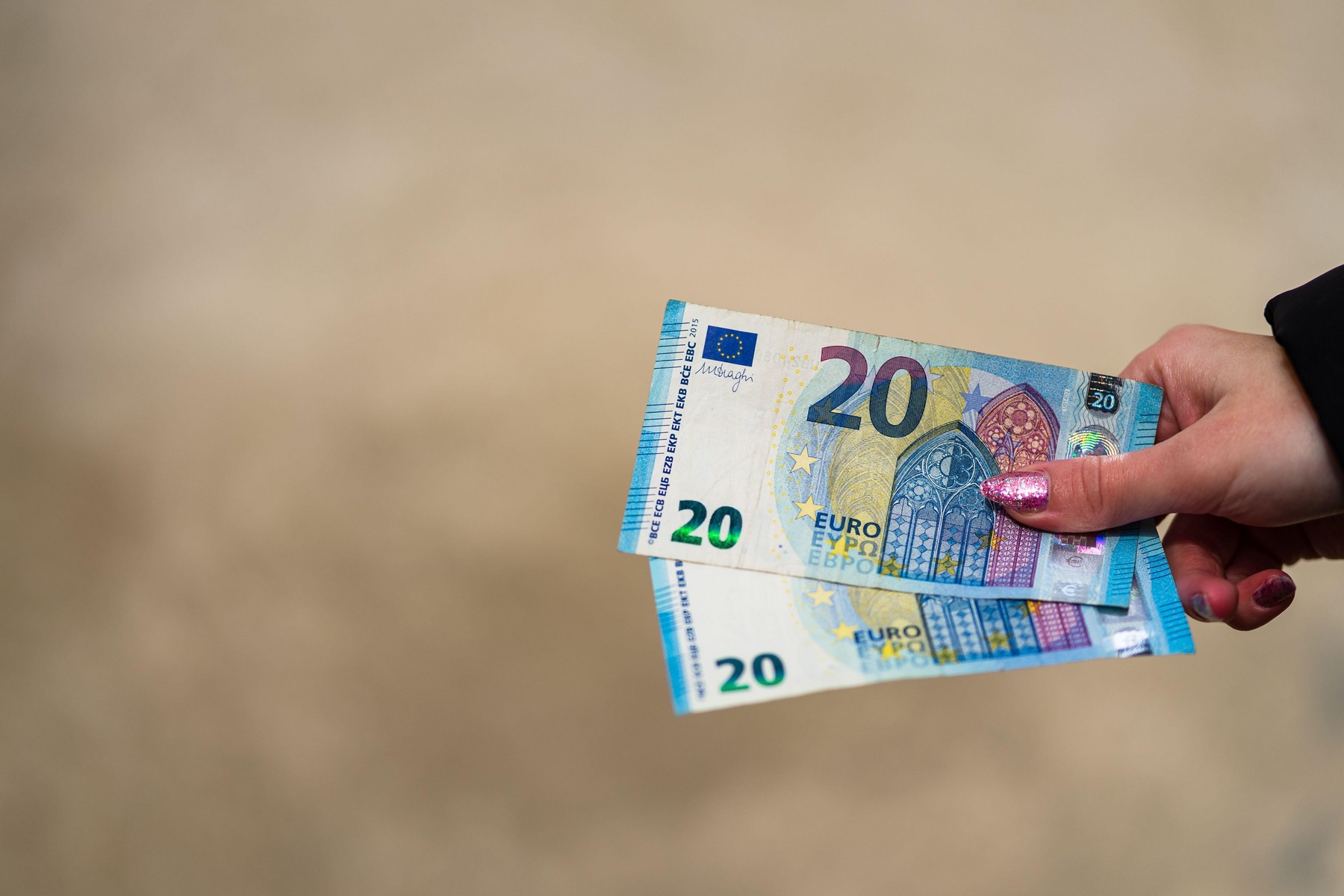 Woman hand holding or giving money like a bribe or tips. World money concept, close up of 20 EURO banknote, photo of EUR currency isolated. Hand holdi