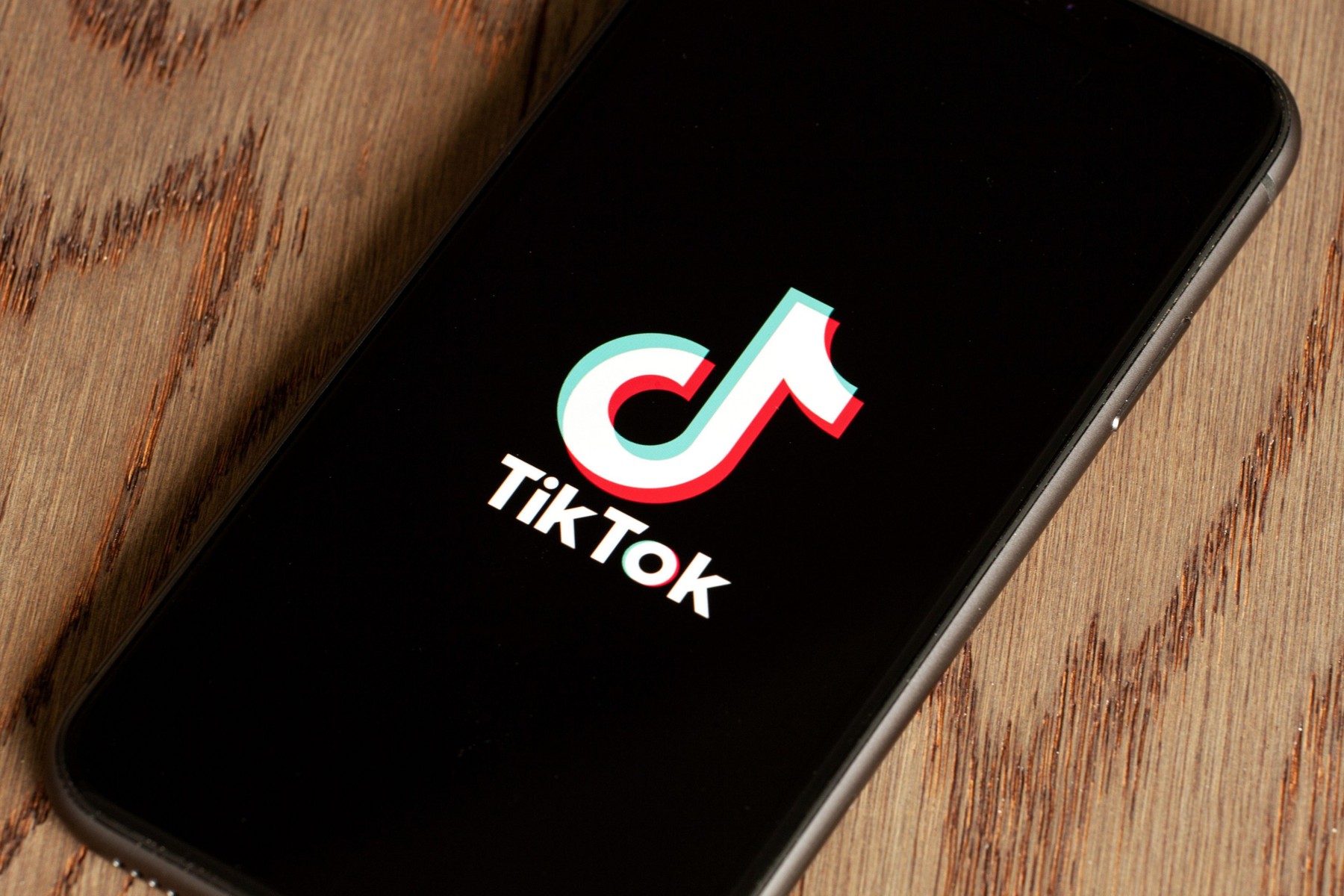 TikTok application icon on Apple iPhone 11 screen close-up. Tik Tok icon on smartphone with wooden backgroung.  Tiktok Social media network from China