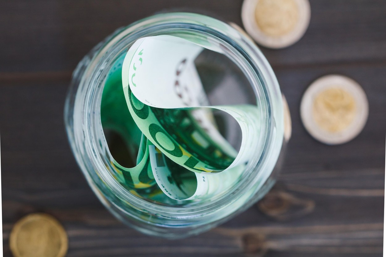 Top view of glass jar for saving Euro money on a wooden dark table.