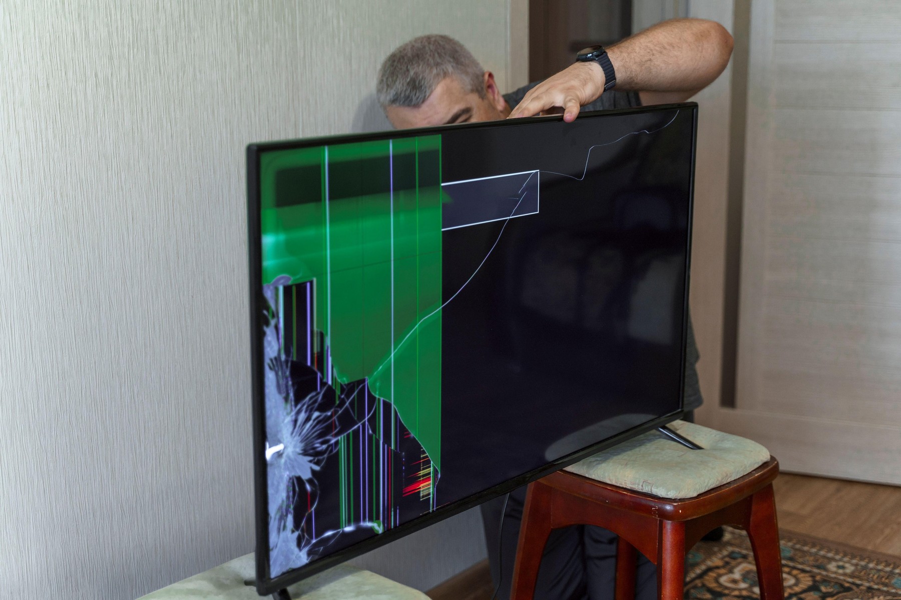 a man trying to fix a broken TV. device screen is broken