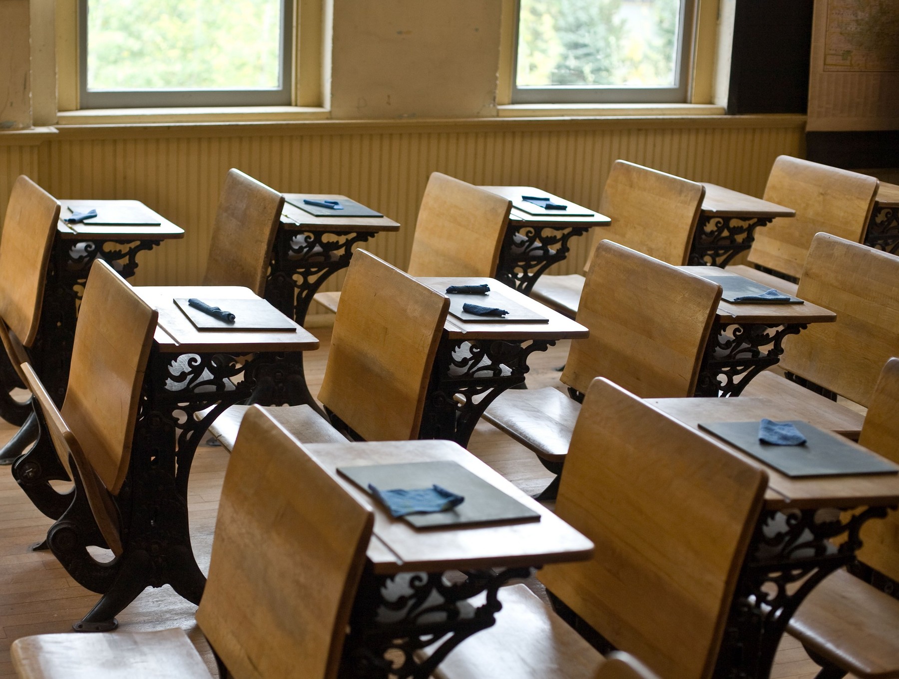 Old classroom with antique chairs and desks with little blackboards on desks for writing.