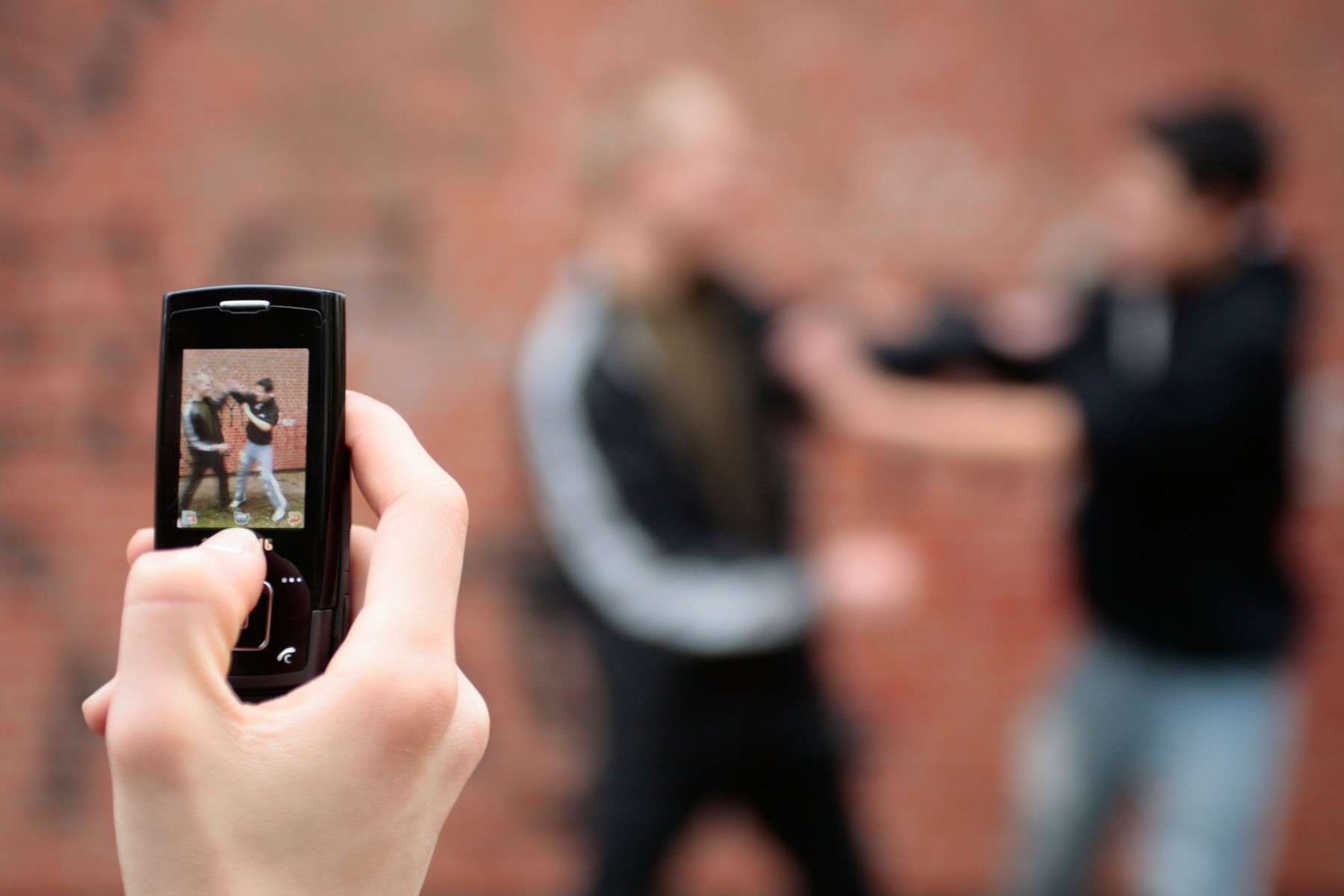 two fighting boys are being recorded by mobile phone