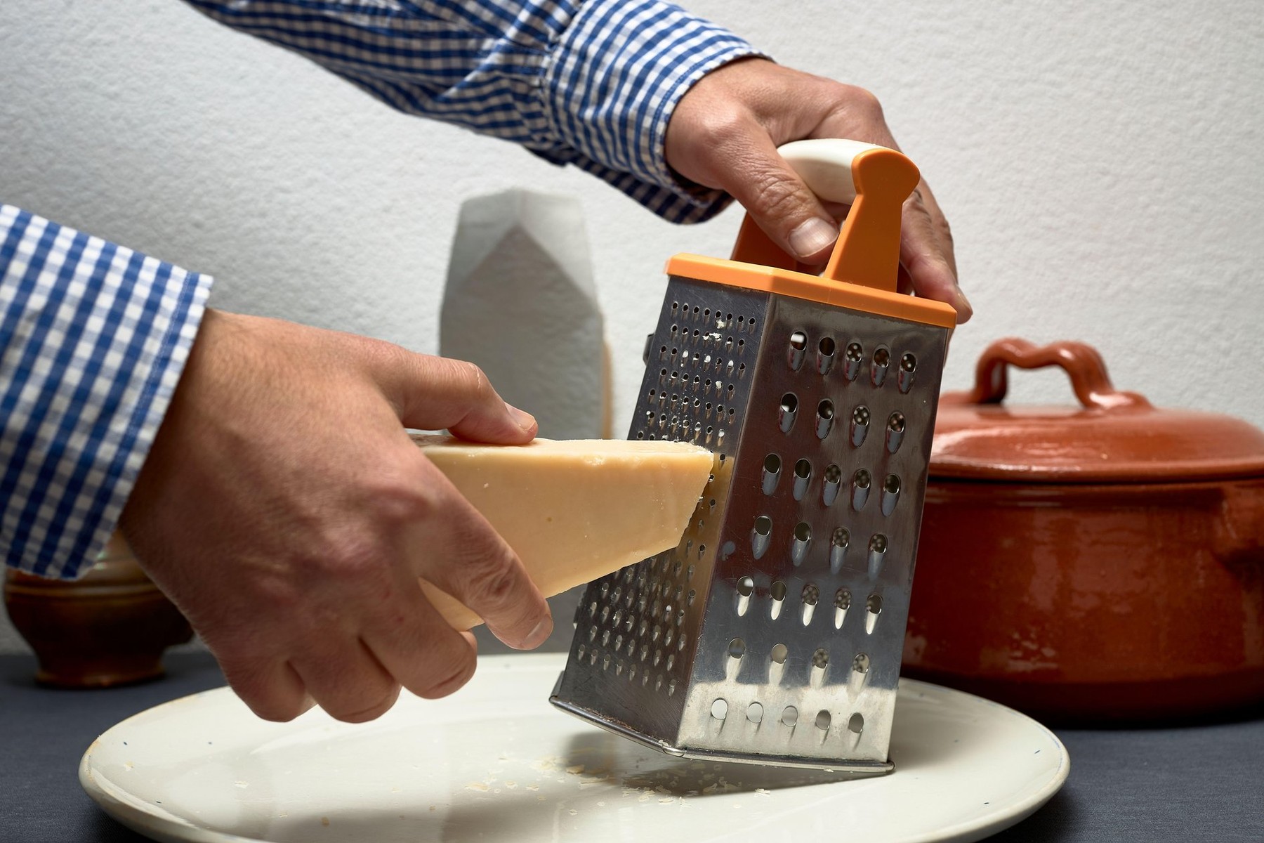 Grating cheese with a metal grater and a piece of Italian cheese