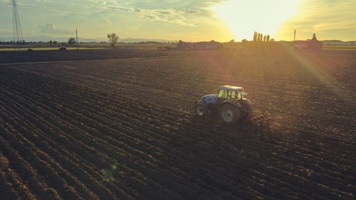 farmer with tractor leveling land in the countryside.