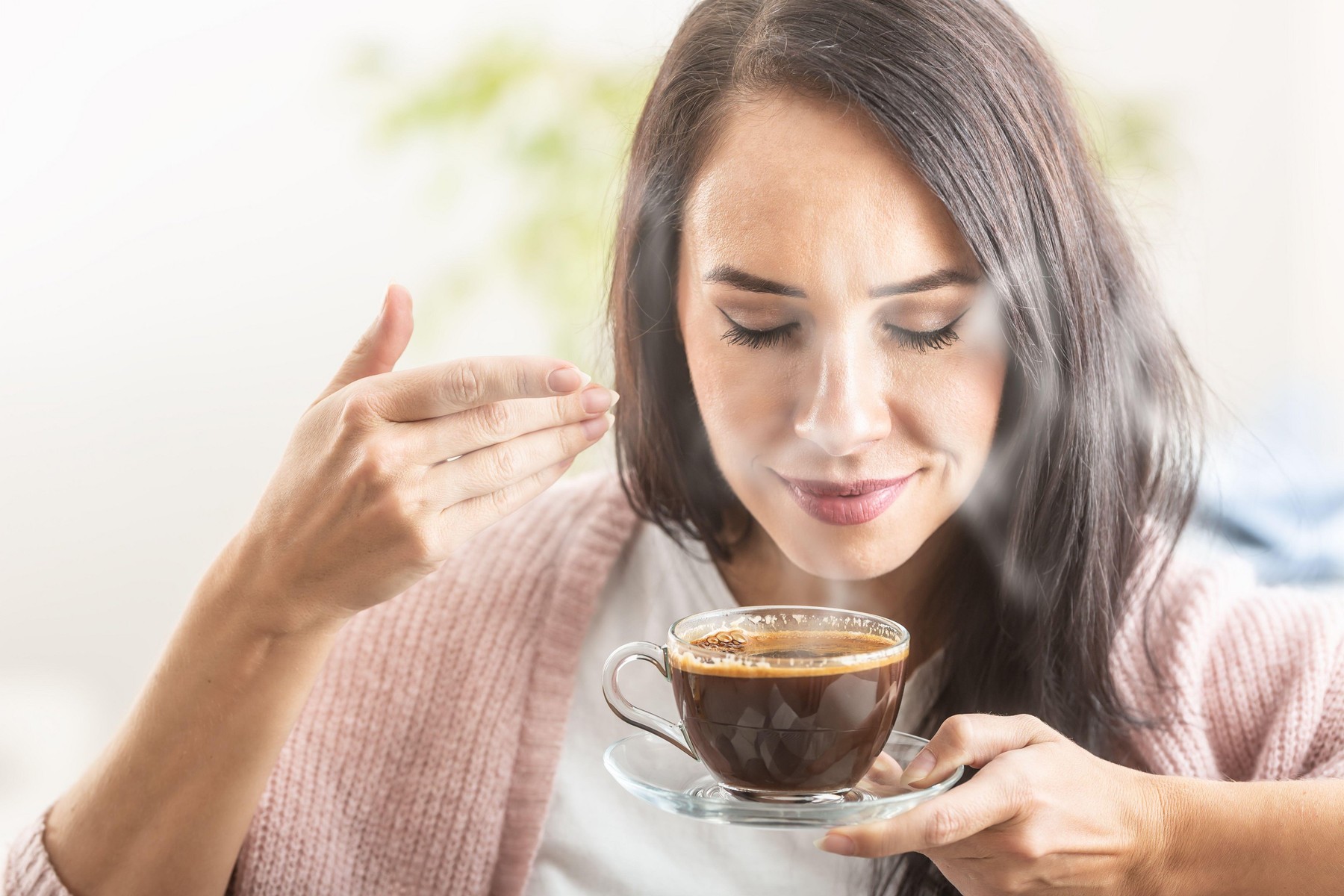 Brunette enjoys the smell of freshly made coffee in a cup.