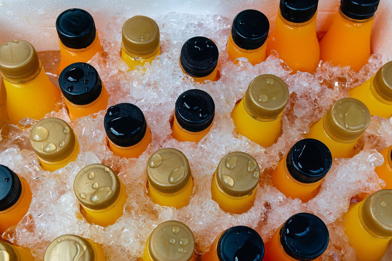 Orange juice or lemonade bottles in a box of ice, close up.