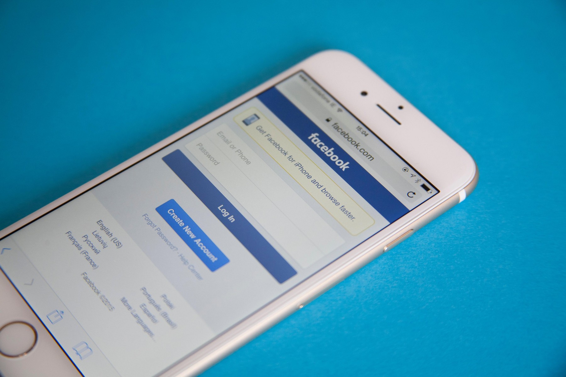 Gold and white Apple iPhone 6 with a Facebook log in screen against a blue background