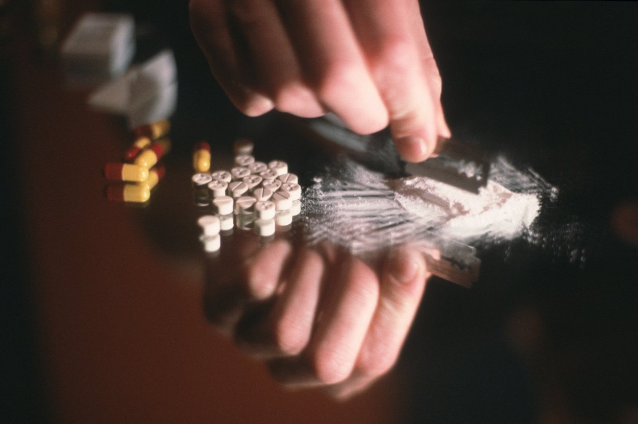 Close up hand cutting cocaine with razor