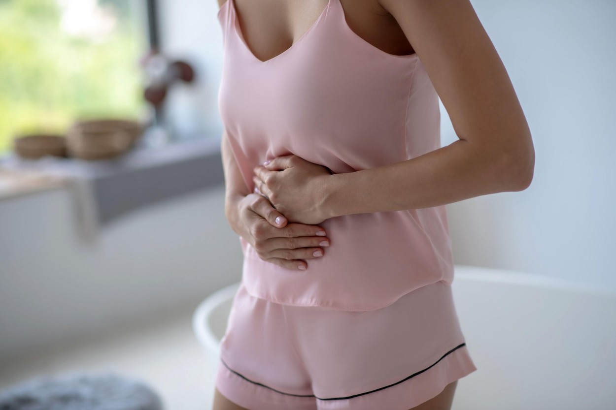Woman in pink lingerie having a stomach ache